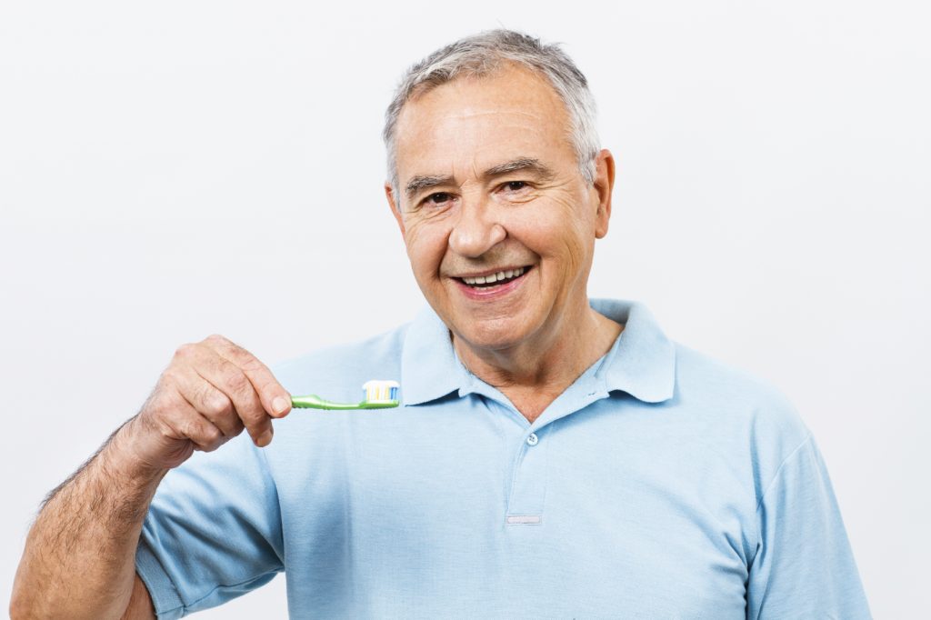 Man smiling holding up toothbrush
