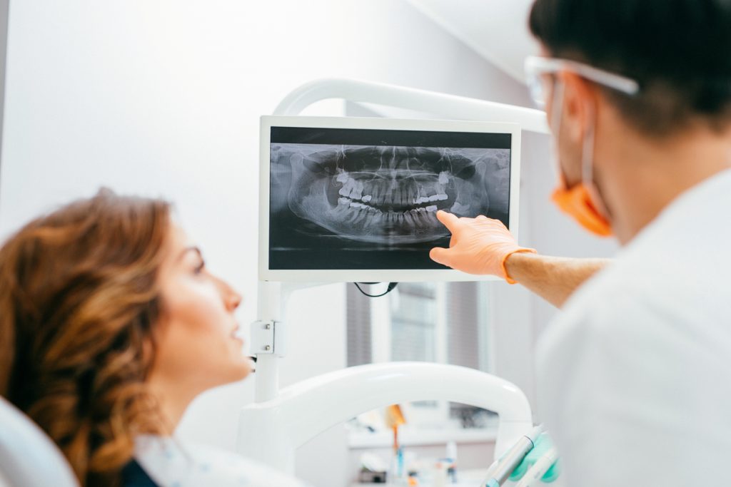 dentist showing woman x-ray of her teeth on monitor