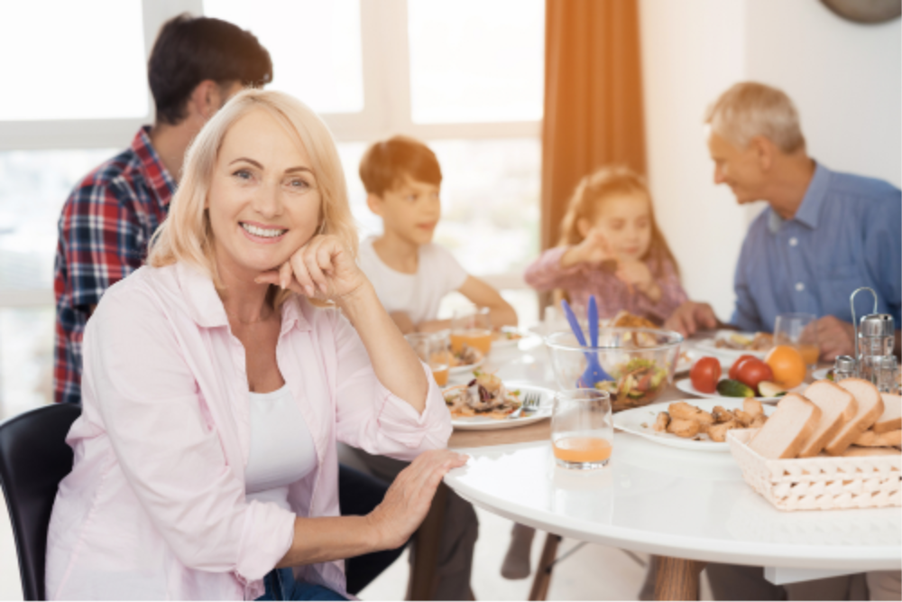Woman with perfect teeth smiling at table with family