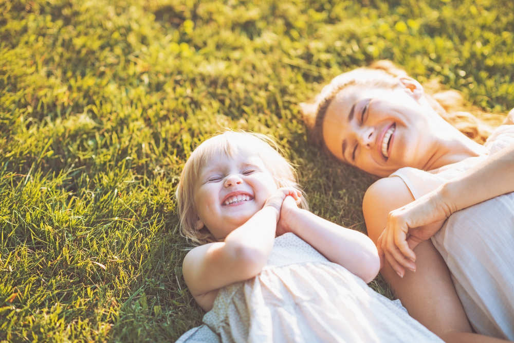 Mother and child laying on grass smiling