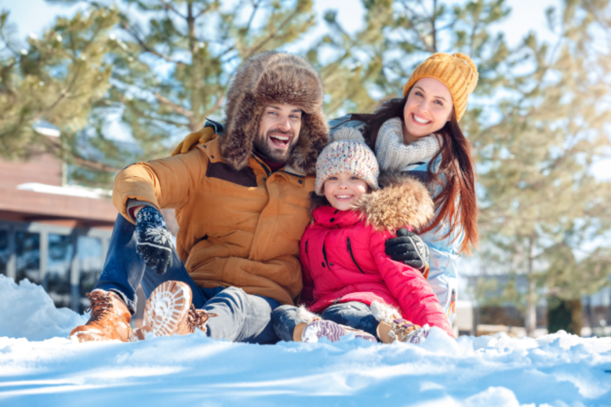 Family smiling while playing in snow