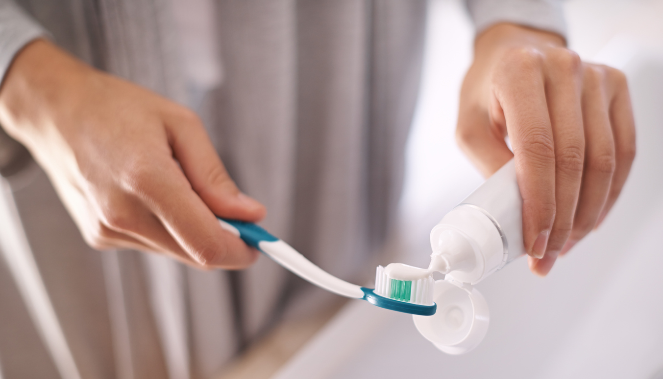 A woman putting toothpaste in her toothbrush