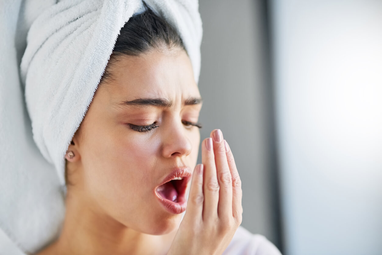 Shot of a beautiful young woman checking her breath at home