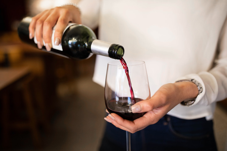 A closeup of a person pouring a glass of red wine