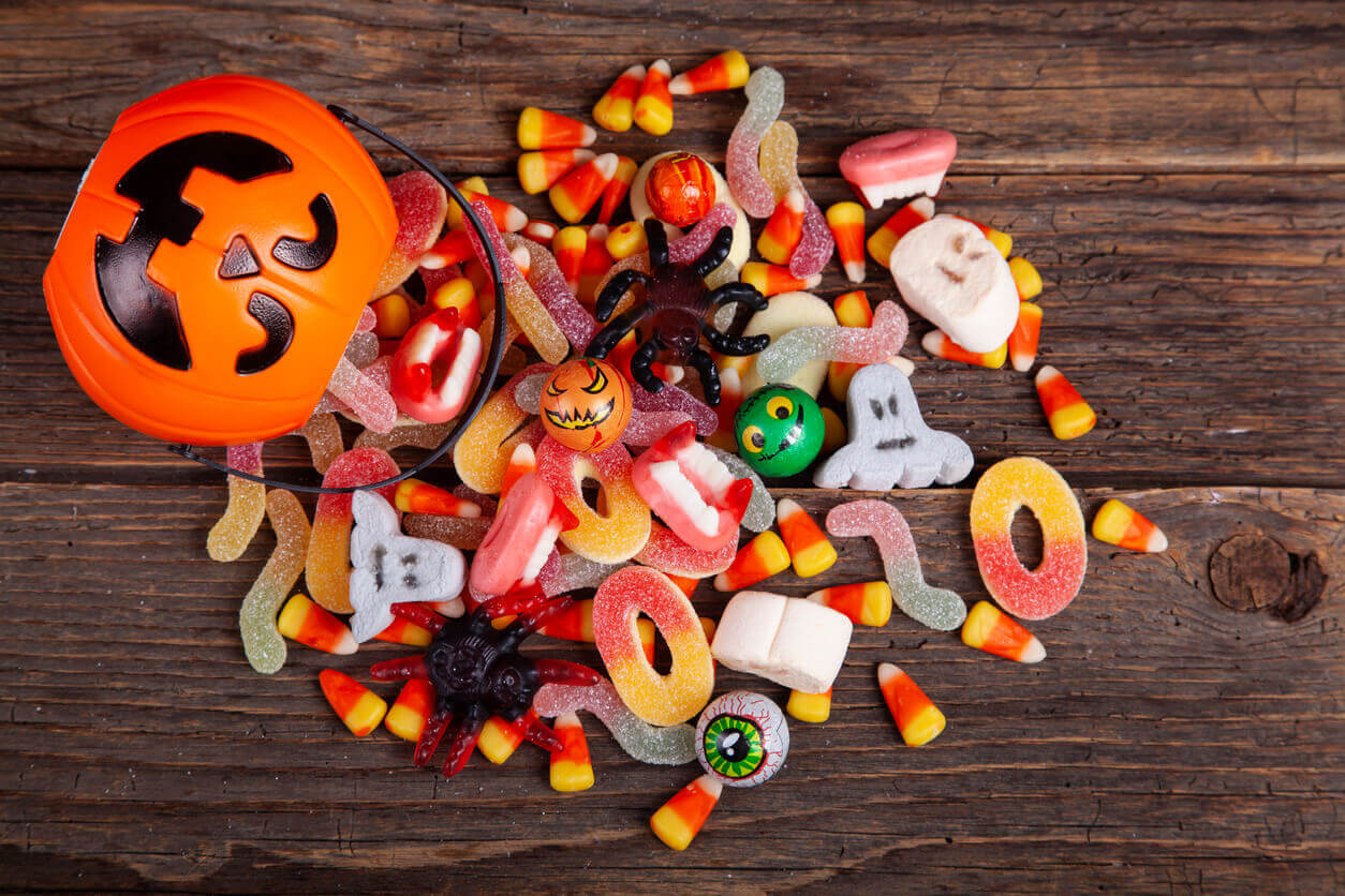 Halloween Jack o Lantern pail with bottom border of spilling candy over brown wood