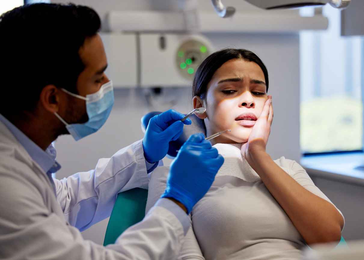 Shot of a young woman experiencing pain and anxiety while having a dental procedure performed on her